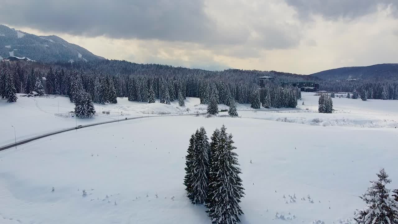 루마니아 포이아나 브라소브에 위치한 배경에 전나무와 두꺼운 구름이 있는 두꺼운 흰색 눈 담요로 둘러싸인 그림 같은 산악 리조트의 공중 전망