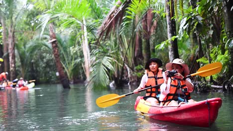 couple kayaking through lush, tropical canal