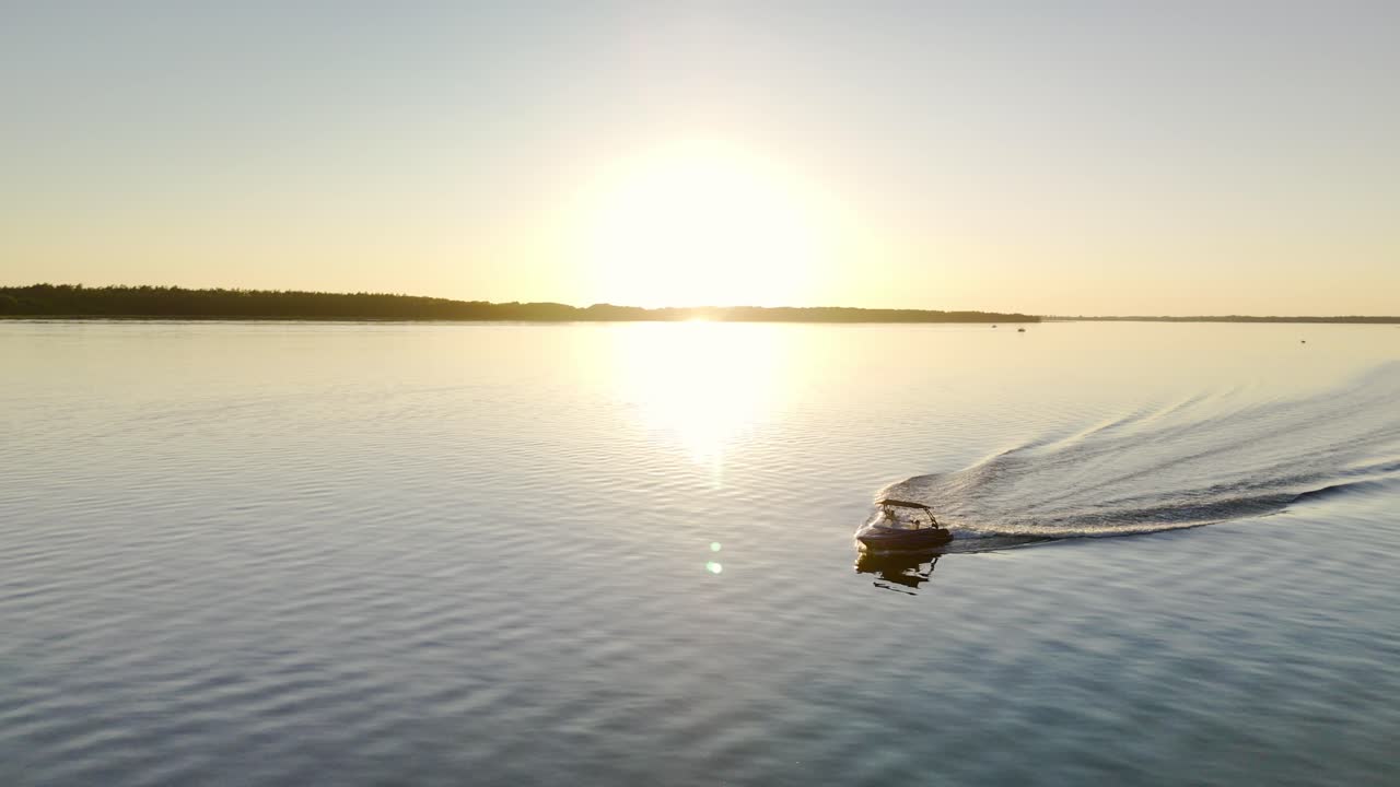 Cinematic Silhouette of Motorboat cruising on Calm Water Lake during golder hour sunset