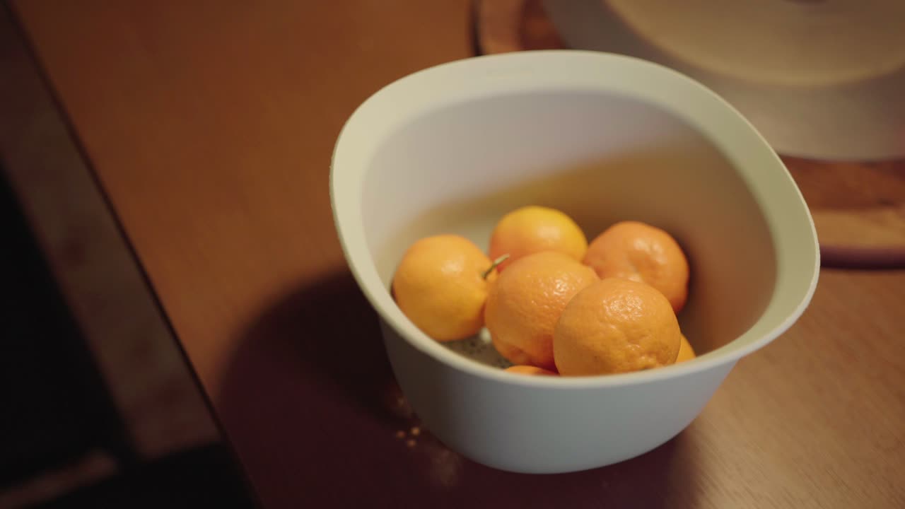 vista de cerca el hombre recoge naranjas en una canasta y toma una de la canasta blanca y la guarda nuevamente en esa canasta que está sobre una mesa de madera