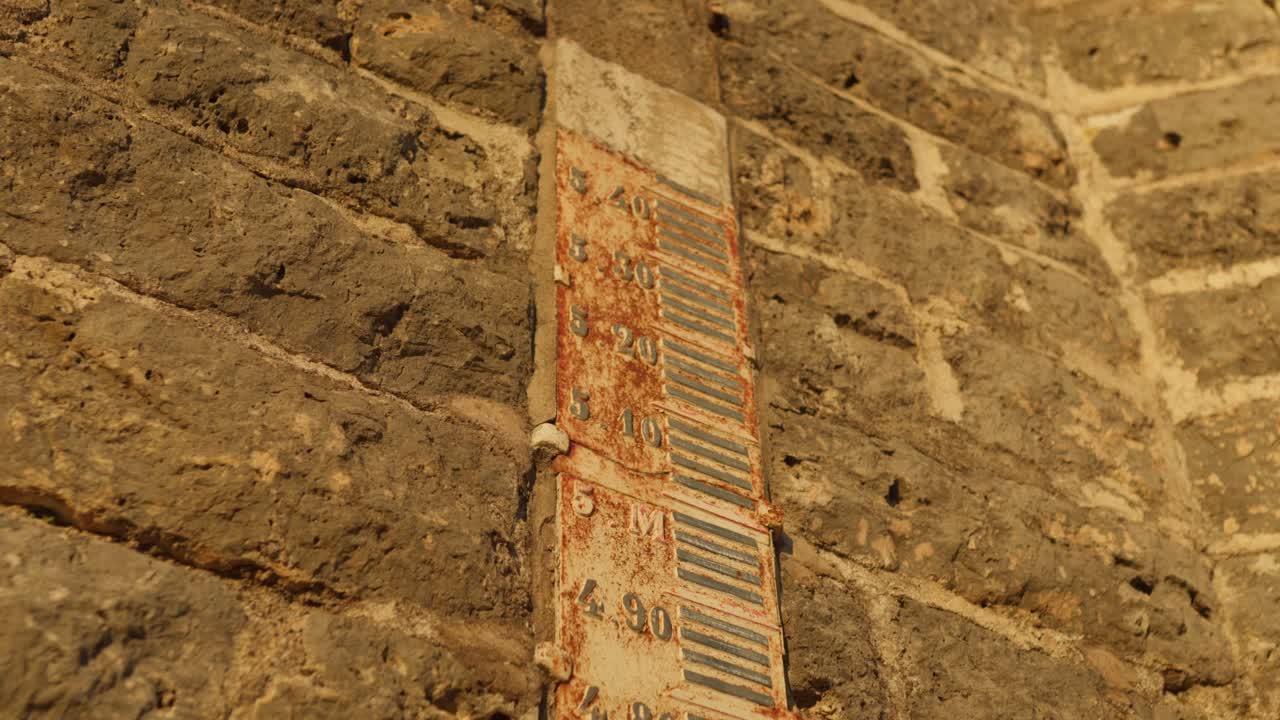 texto numérico en la pared de ladrillo que denota los niveles de agua