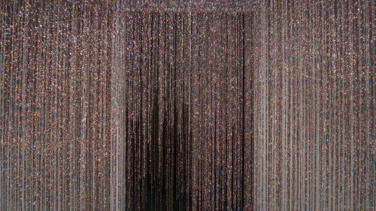 Flickering light making beaded curtain shimmering and shifting inside doorway showing dark gap