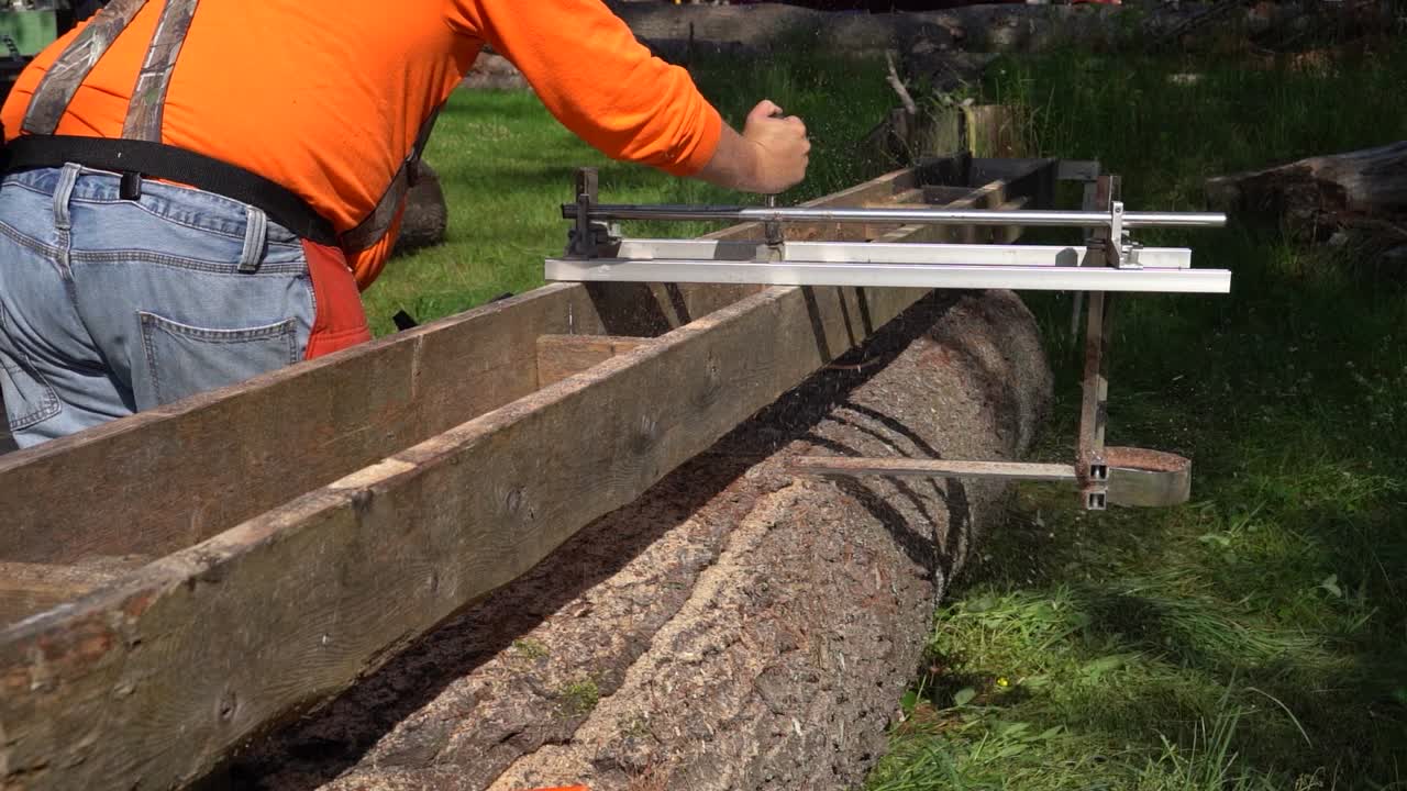 disparo trasero de un artesano de granja moliendo un tronco de pino usando un equipo de molienda casero en cámara lenta
