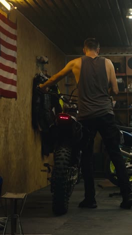 man working on a dirt bike in a garage
