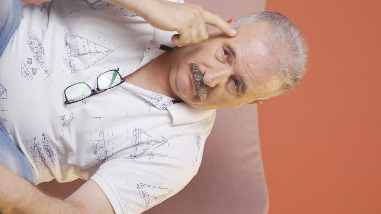 video vertical de un anciano pensativo hacia la cámara viene con una idea.