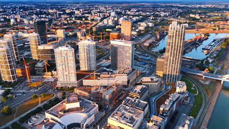 approaching the high-rises with sunlit facades in the cityscape of bratislava, slovakia. several buildings are being constructed. aerial view