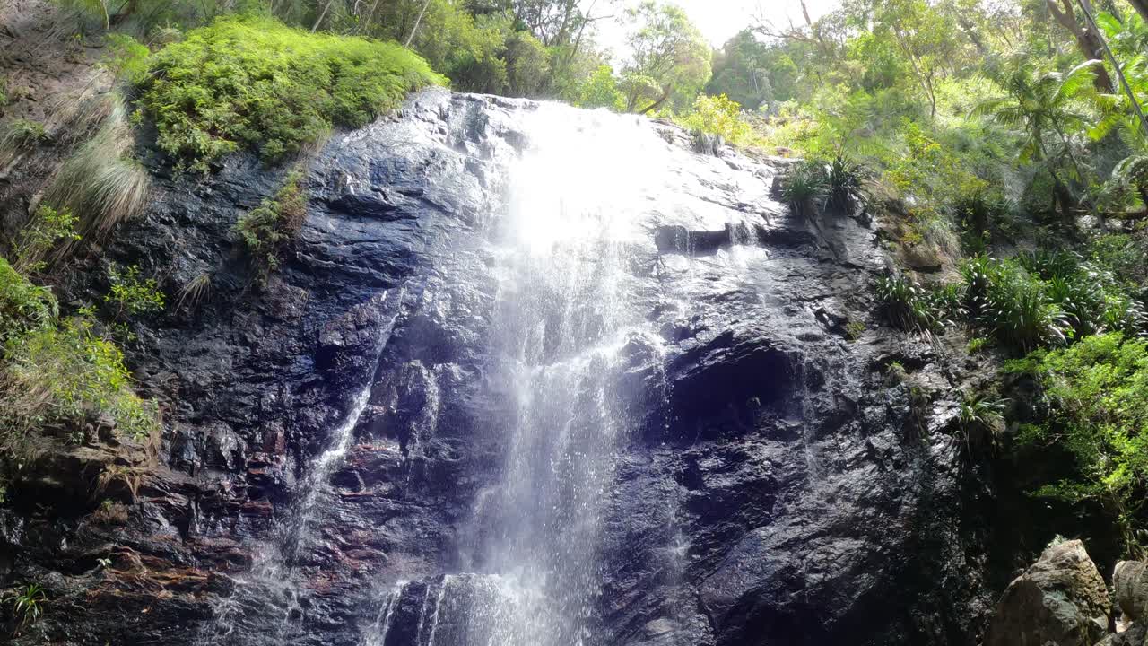 una cascada que fluye sobre un acantilado rocoso rodeado de vegetación