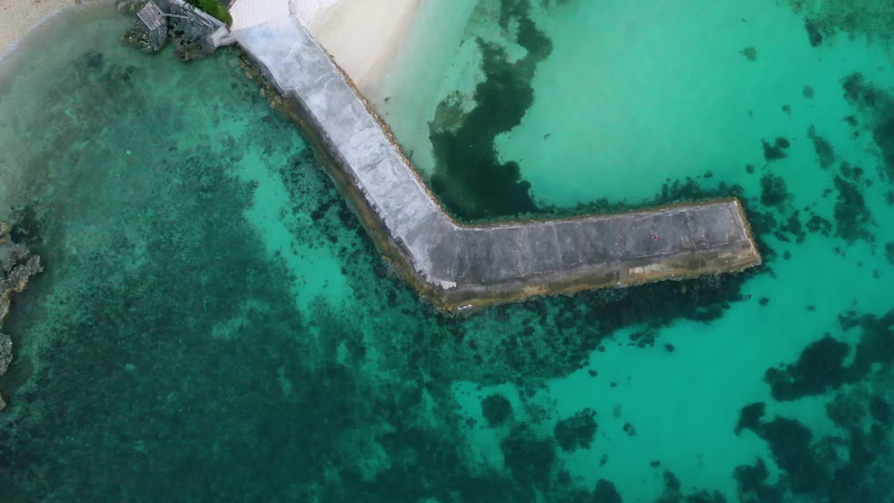 Tranquil pier surrounded by crystal clear tropical sea water. Vertical zoom out