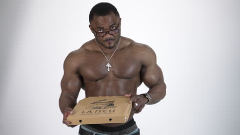 Athletic man with fast food. African handsome naked man eats pizza