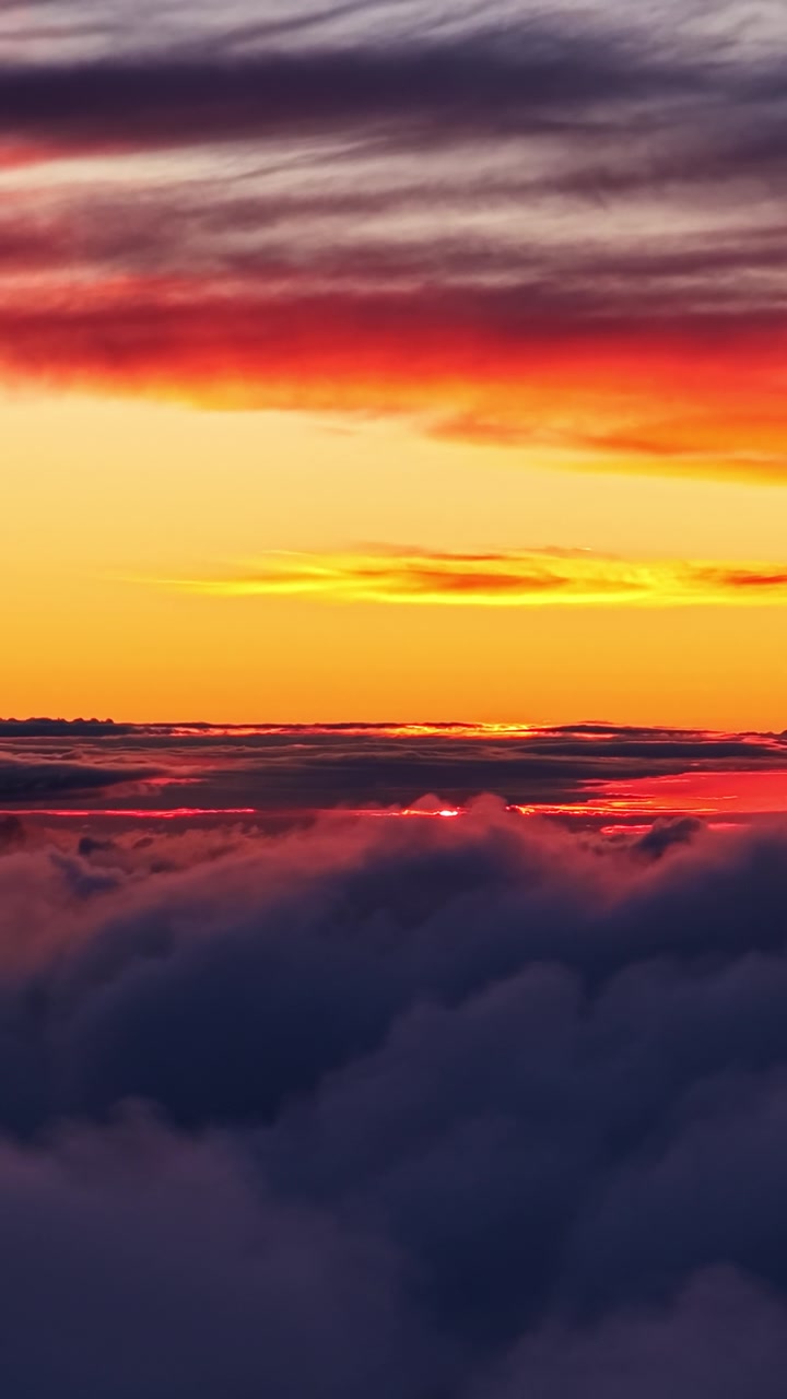 Lebhaftes orange-rotes Abendrot über Wolken aus der Vogelperspektive