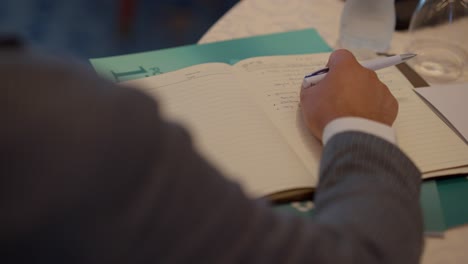 A-man-sitting-in-front-of-his-laptop-and-folding-a-paper-at-home-close-up-shot