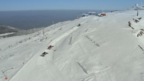 aerial view of snow groomers preparing ski slopes on a mountain resort