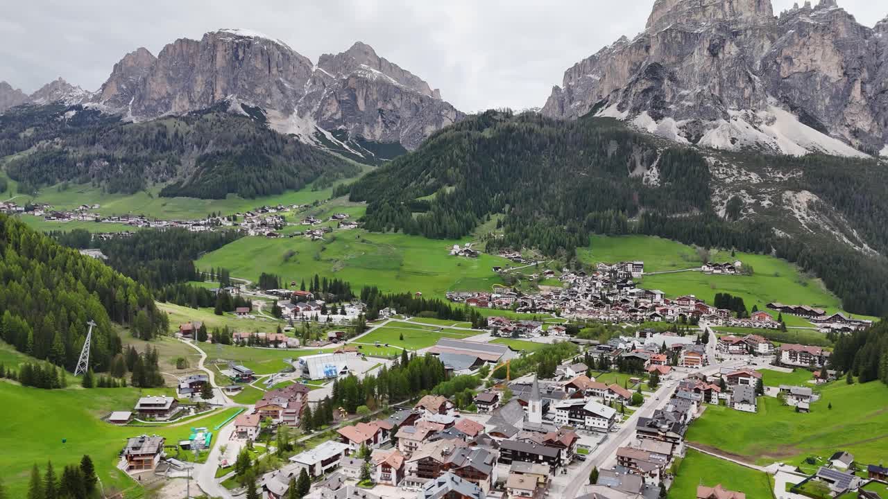 Scenic Corvara in the Dolomites with houses, meadows, and a prominent rocky peak