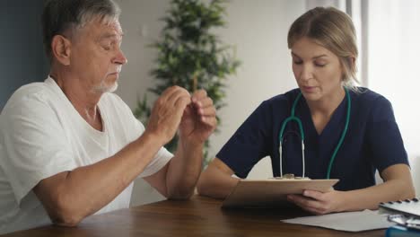 Die-Kaukasische-Ärztin-Informiert-Den-älteren-Patienten-Beim-Hausbesuch-über-Das-Bett.