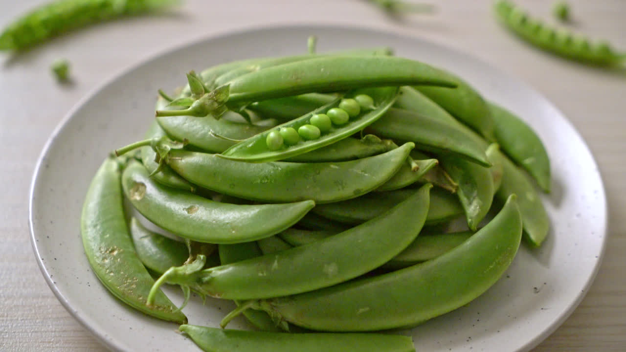 하얀 접시에 신선한 달콤한 녹색 완두콩