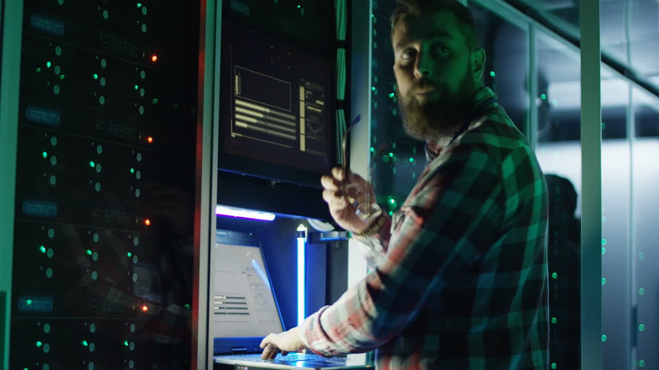 IT Specialist Working in a Server Room at Night