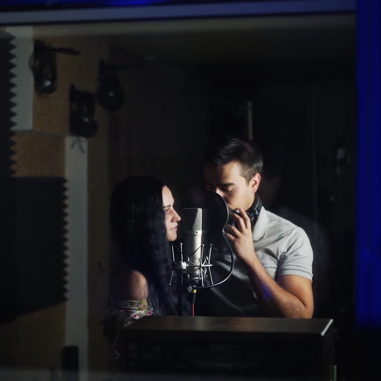 Professional equipment for sound analysis in music recording studio. Close up. Duet in the window stands at the microphone ready for song record