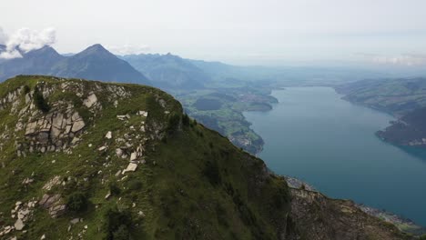 fotografía aérea circulando el pico de morgenberghorn, suiza, revelando las empinadas y dramáticas laderas justo al lado de un río azul y turquesa que corre junto a pequeñas aldeas en la distancia