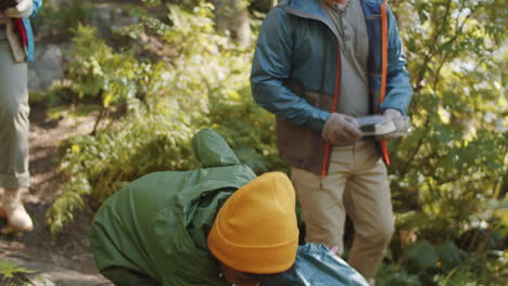 padres multiétnicos y un niño limpiando el campamento en el bosque