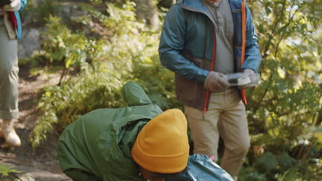 multiethnic parents and kid cleaning up campground in forest