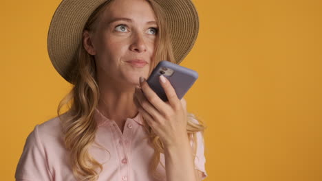 caucasian woman in a hat recording a voice message.