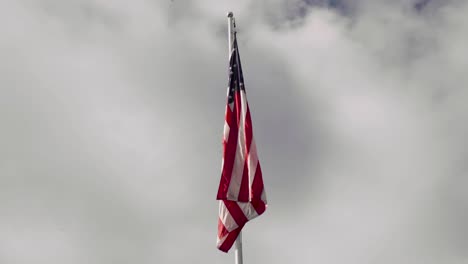 american flag at the top of a flagpole on a calm cloudy day