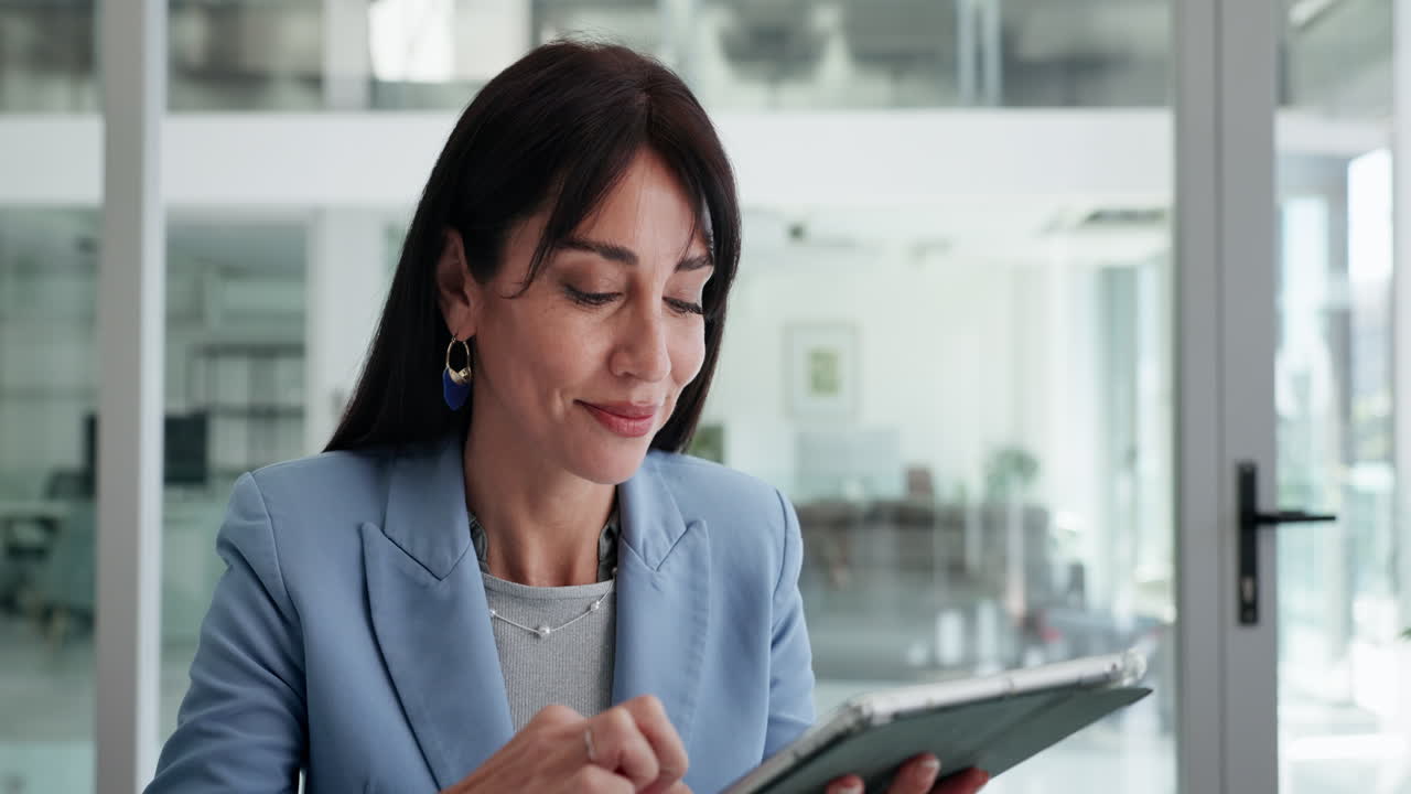 Riflessiva donna d'affari che utilizza un tablet digitale in un ufficio moderno