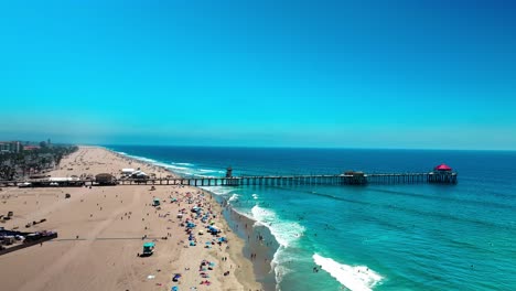 Drohne-Fliegt-Den-Strand-Hinunter-Und-In-Richtung-Des-Piers-In-Huntington-Beach,-Kalifornien