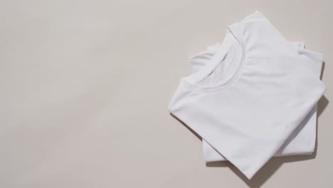 Video-of-stack-of-folded-white-t-shirts-with-copy-space-on-white-background