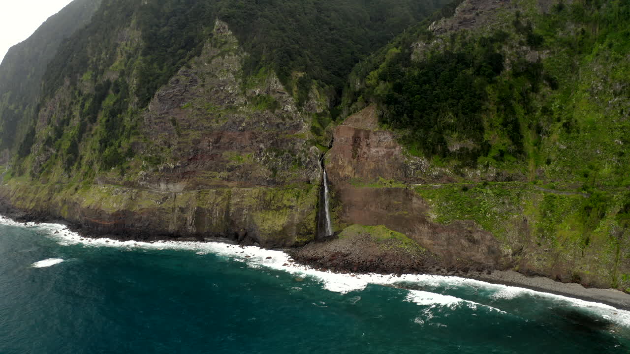 Drone footage of Véu da Noiva waterfall on the north coast of Madeira, Portugal, with huge mountain on the coast