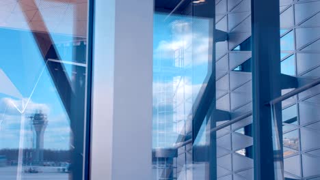 the glass of waiting hall of the airport reflects the runway with airplanes