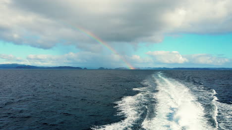 Viajando-A-Través-Del-Océano-Azul-En-La-Bahía-De-Islas-En-Nueva-Zelanda-Con-Una-Vista-Lejana-Del-Arco-Iris-En-El-Fondo