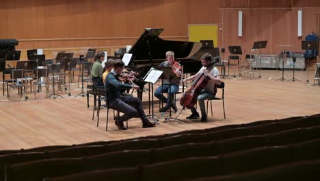 a string quartet with a grand piano rehearsing before the performance