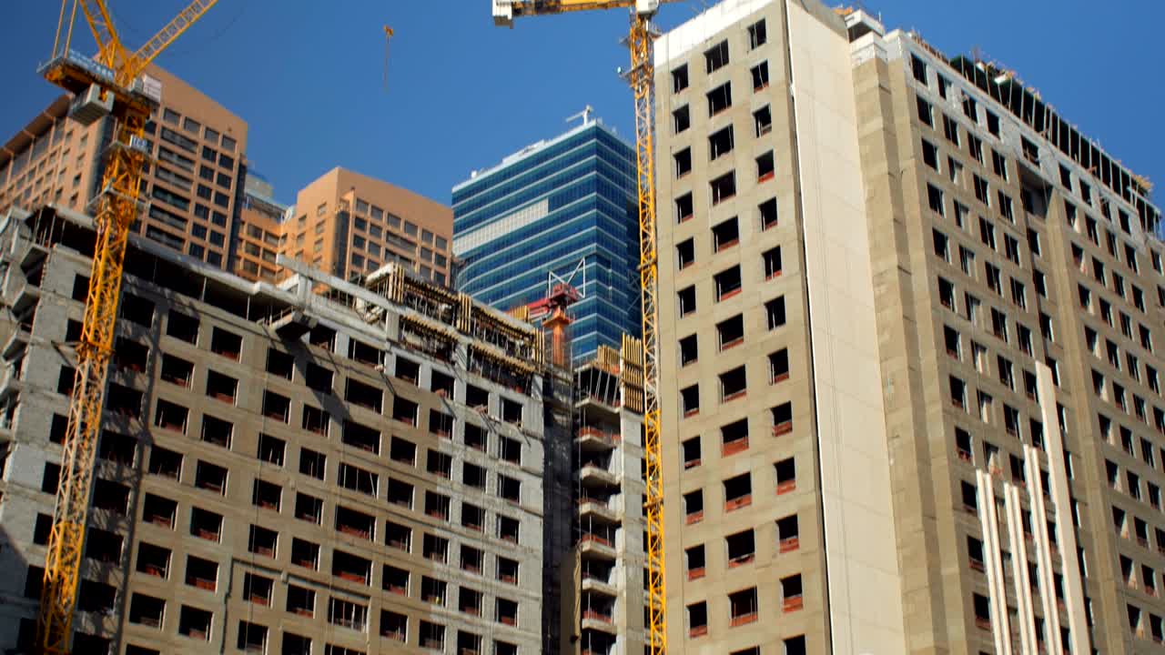 panorama inclinado de edificios altos en construcción en el centro de la ciudad moderna en un día soleado
