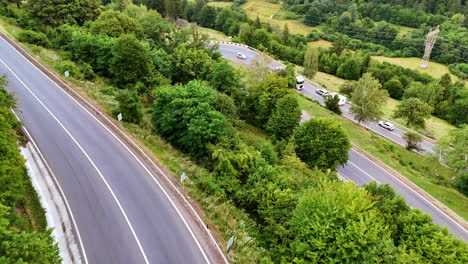 truck on winding road through trees. a red truck drives along a curvy road surrounded by lush green trees in a scenic landscape