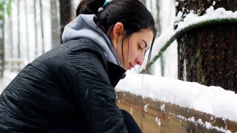 Beautiful-woman-tying-shoelaces-during-snowfall