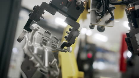 slow close up of a metallic part being held by a robot arm in an industrial production facility