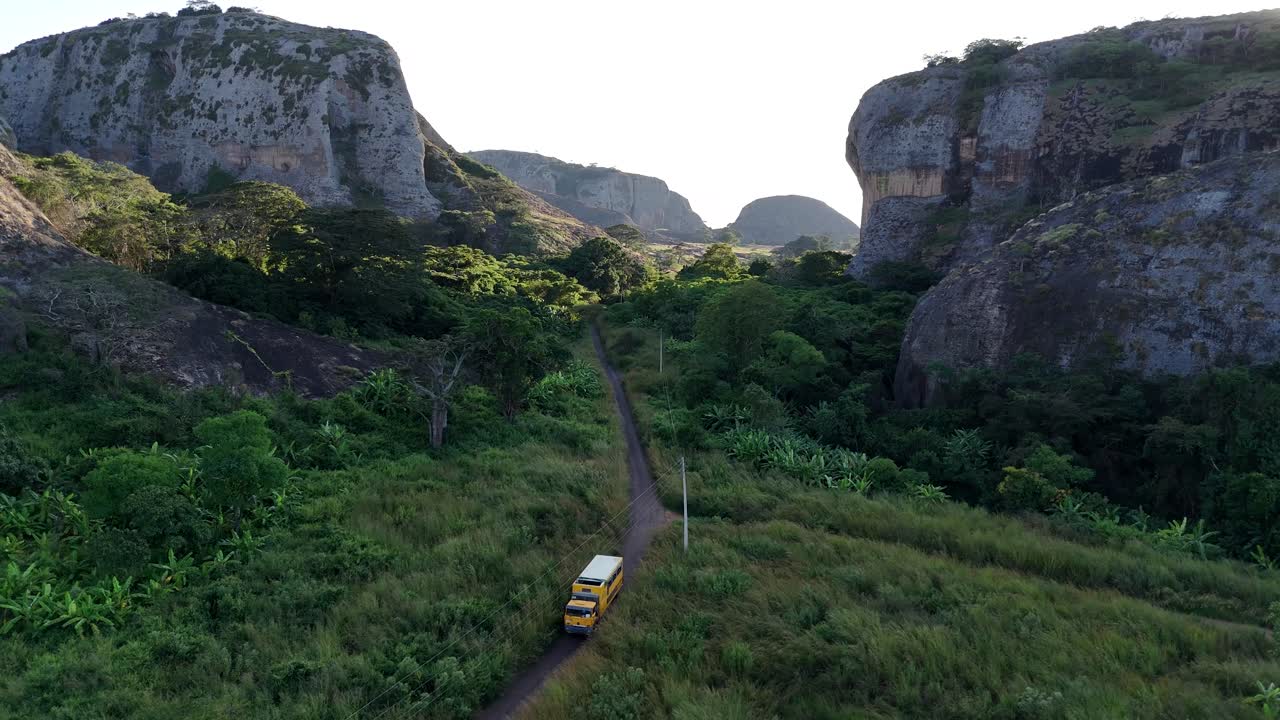 Suggestiva ripresa aerea dei monoliti Pedras Negras de Pungo Andongo nella provincia di Malanje, Angola, Africa, con un camion camper sovraccarico che percorre uno stretto sentiero fuoristrada