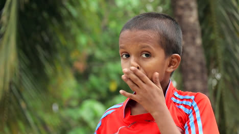 a local indian boy wearing a t shirt and smiling at camera.