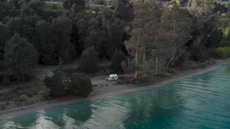 motorhome on beach beautiful blue lake wakatipu, queenstown, new zealand and trees scenery during fall autumn - aerial drone