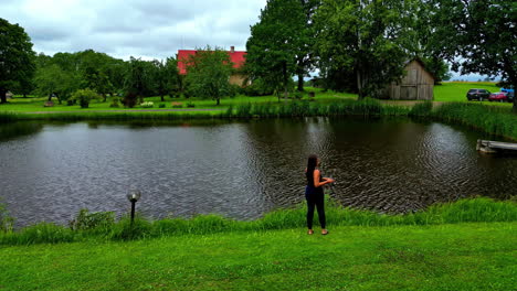 Fishing-Brunette-woman-using-fishing-rod-and-pole-at-fish-pond-in-rural-setting