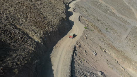 Aerial-shot-of-vehicle-on-Fairy-Meadows-Road-in-Pakistan,-second-deadliest-highway-in-the-world,-starting-downward-then-revealing-wide-drone-shot