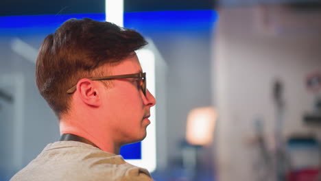 person focused on video equipment in tv studio, seated and adjusting settings on monitor. seen from behind, studio lights and equipment visible in background, working with controls