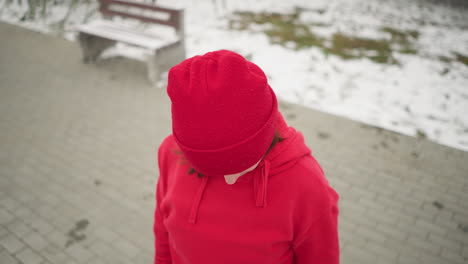 woman turns head from right to left slowly with eyes closed, focusing inward in a calm and meditative state, snowy background features benches and frosted trees