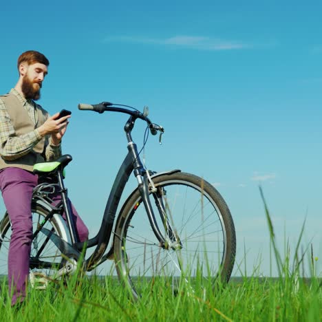 a young man uses a smartphone travels by bicycle