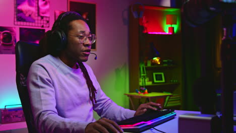 man playing video games in a dimly lit room with colorful lights