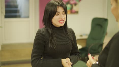 professional female manager in a black formal outfit, walking through the office, interacting with colleagues, holding documents and a laptop, showcasing leadership and professionalism