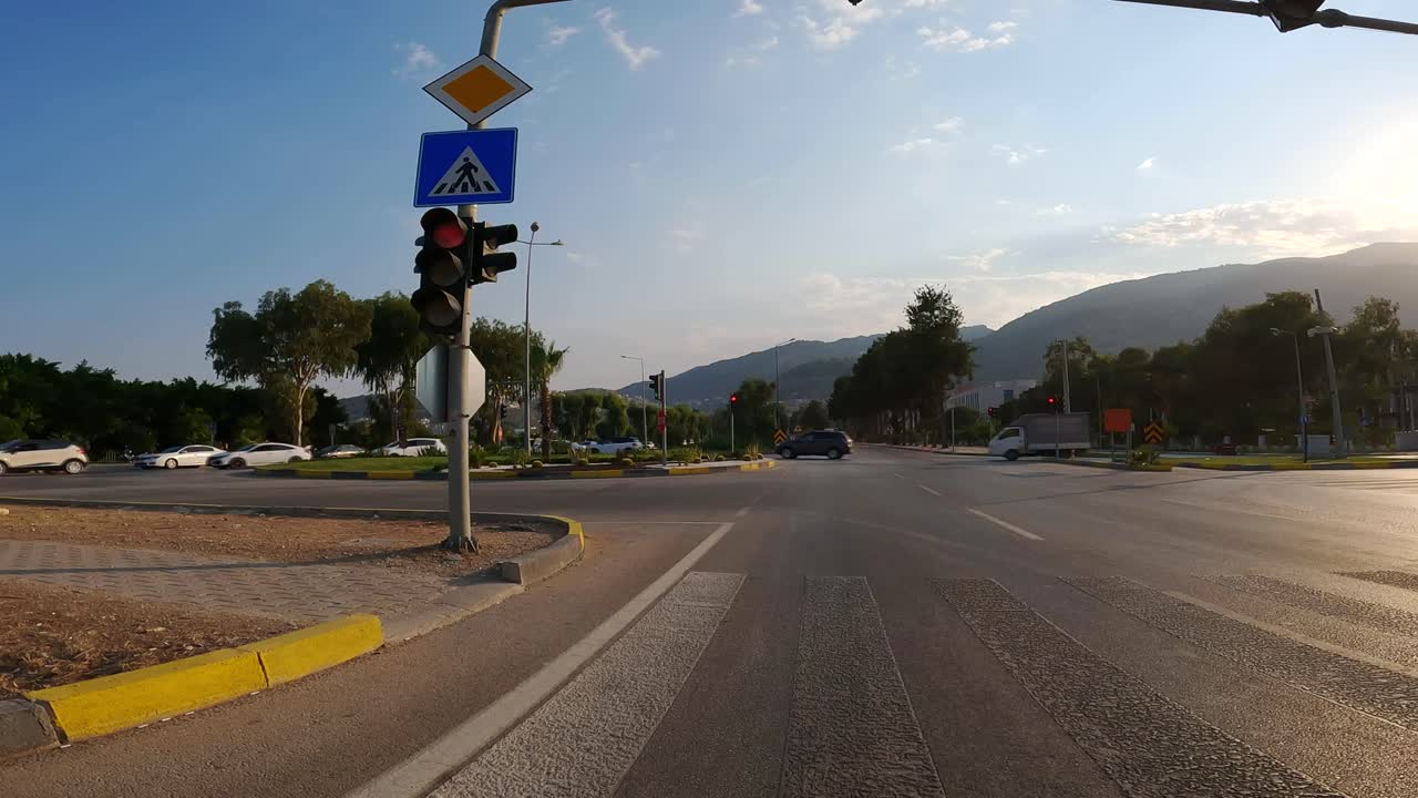 una vista desde un vehículo de una luz roja en una intersección. en el fondo, el tráfico urbano en un caluroso día de verano