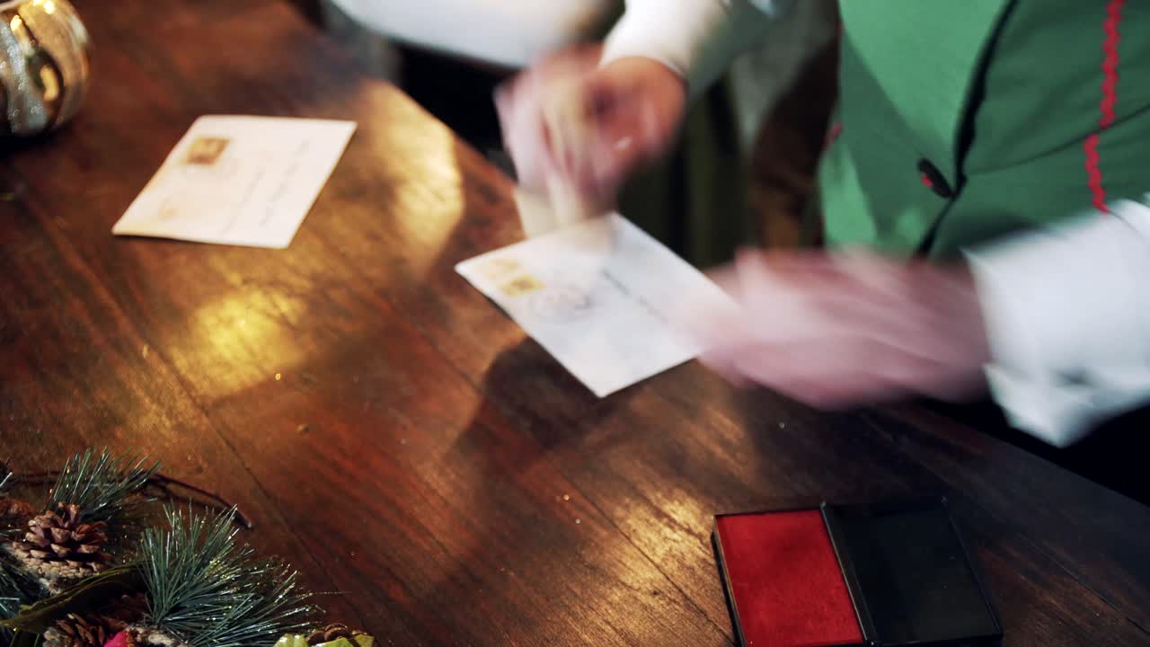 Elf putting seal on the envelope. Letters for kids on the table before Christmas. Santa's residence. Close-up