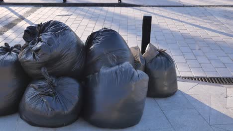 pile of black garbage bags on city street